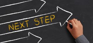 "Next Step" written inside an arrow on a chalkboard